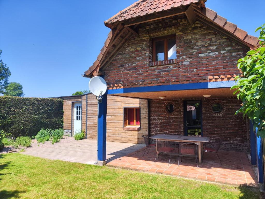 a brick house with a picnic table on a patio at Le gîte des hallais in Bouelles