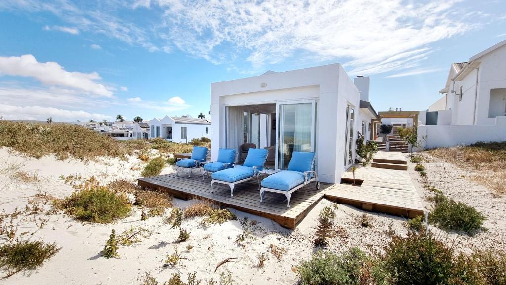 a group of blue chairs sitting on a deck in the sand at Ashore - Beachfront Paradise in St. Helena Bay