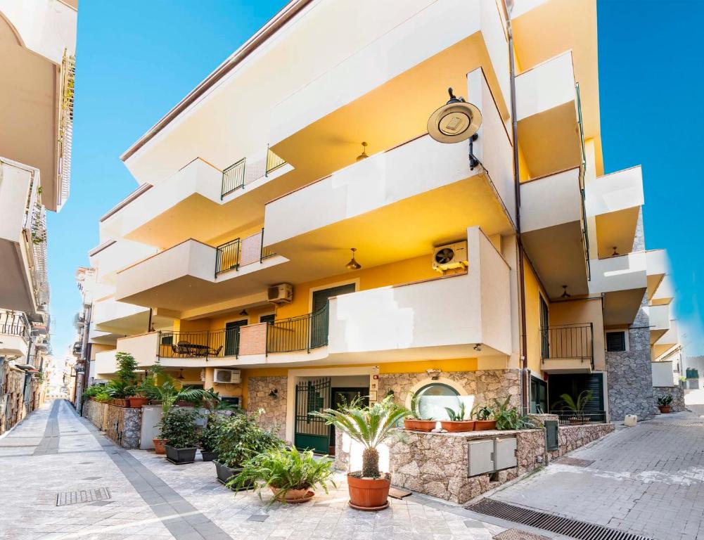 an apartment building with white and yellow at Le Tartarughe Aparthotel in Letojanni