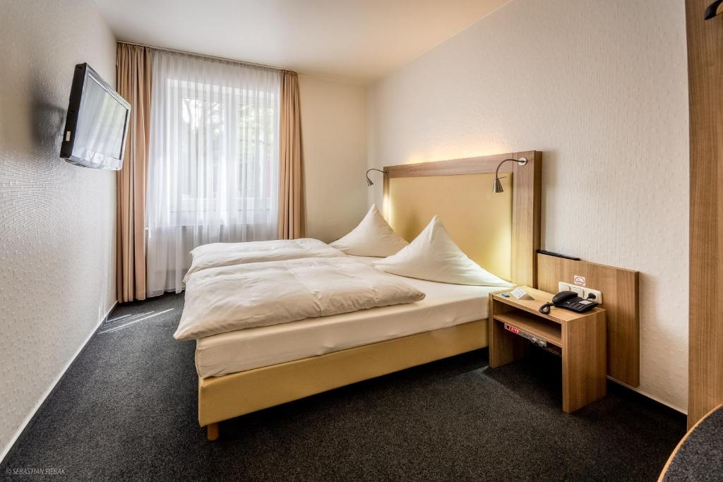a hotel room with a bed and a night stand at Hotel Lousberg in Aachen