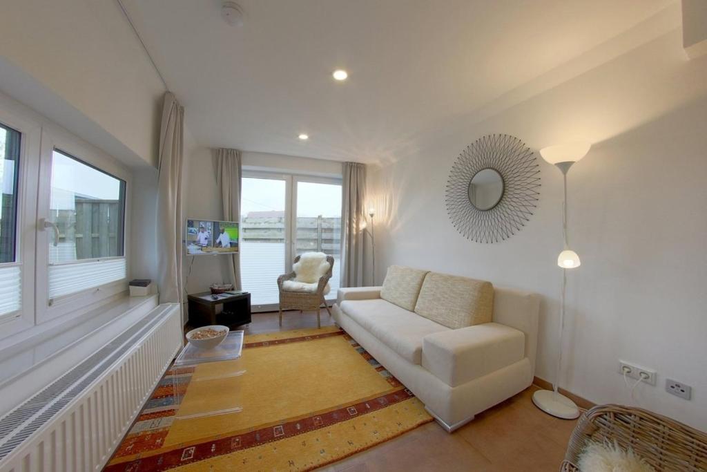 a living room with a white couch and a chair at NS 6a Seestern Wremen in Wremen