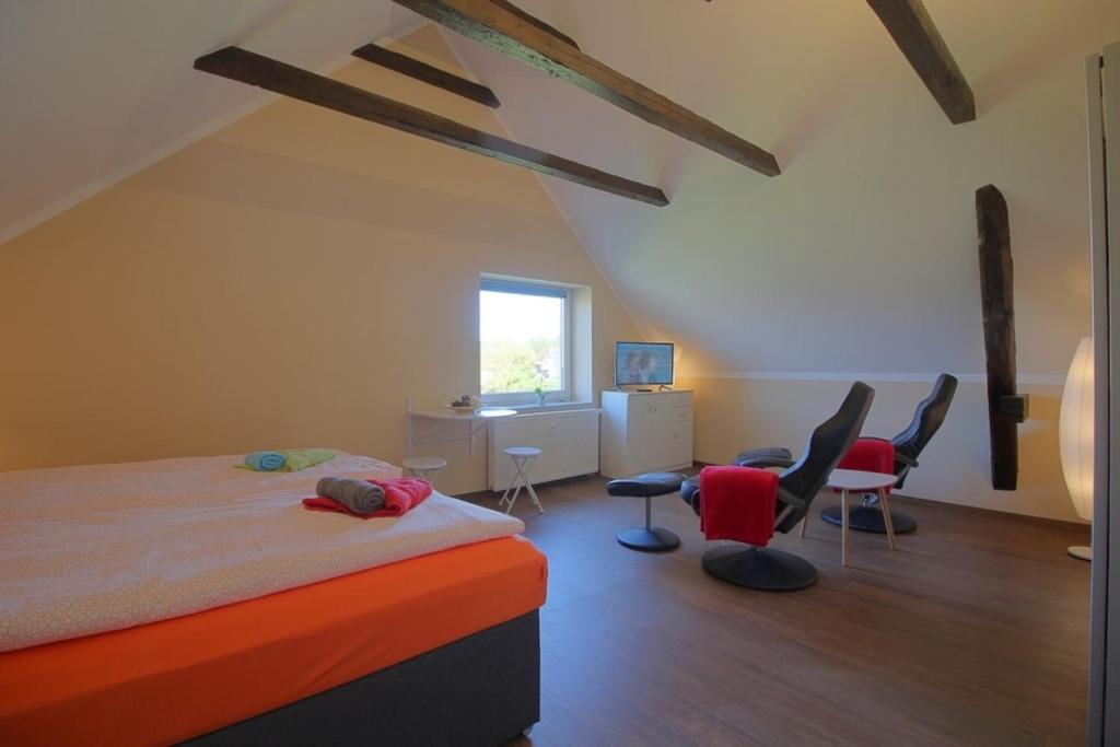 a bedroom with a bed with chairs and a desk at Gästehaus Dorum 05 in Dorum