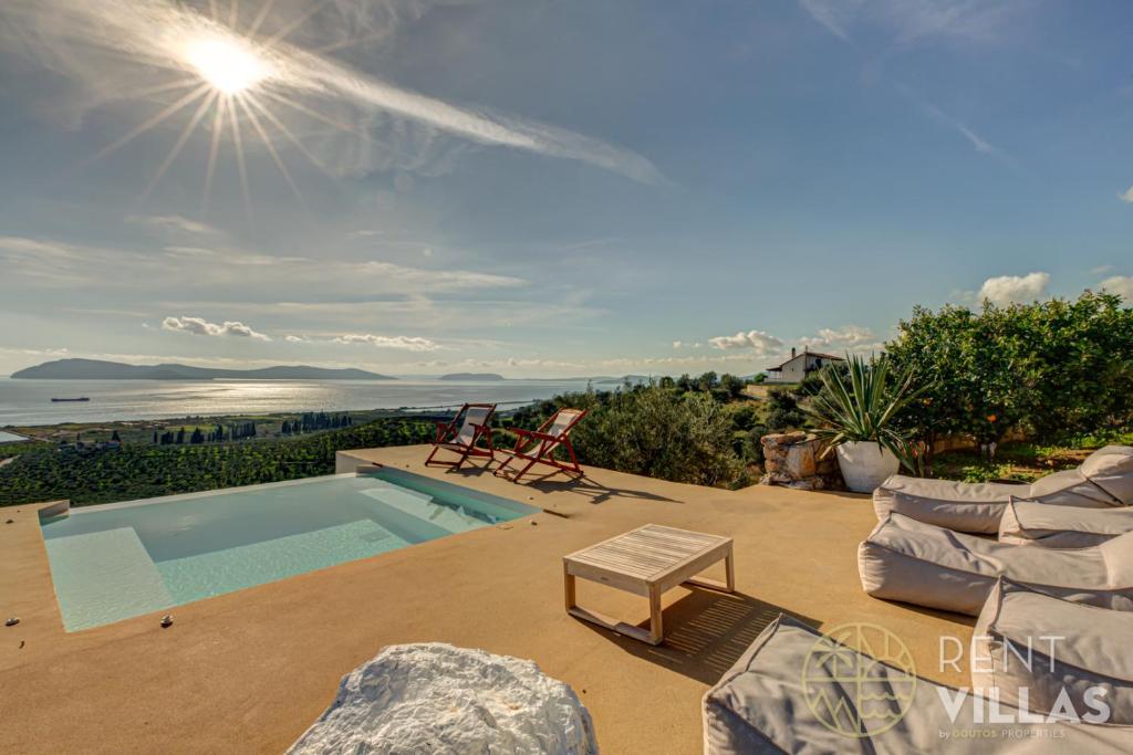 an outdoor patio with a pool and a table and chairs at Villa Karima with Sea View in Metókhion