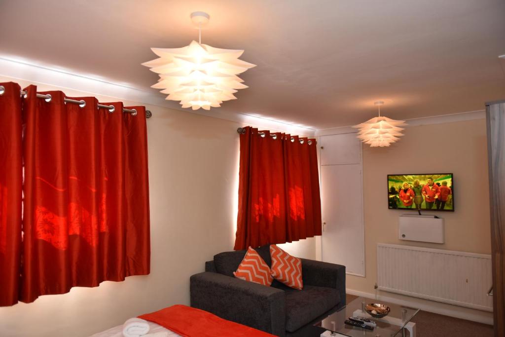 a living room with red curtains and a chair at Everest House in Canterbury