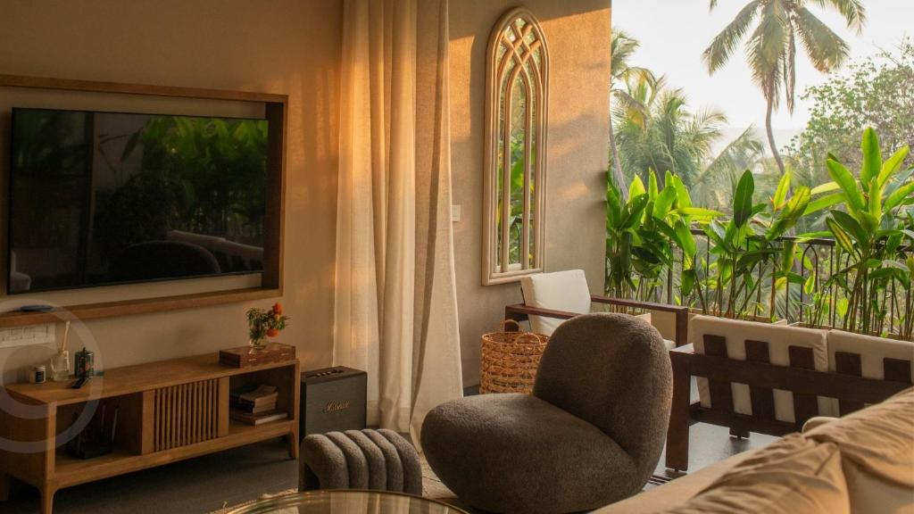 a living room with a television and a chair at The Ten in Siolim