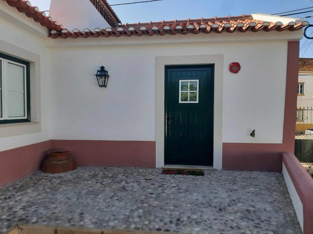 a green door on a white house with a roof at Casas do Hastim in Golegã