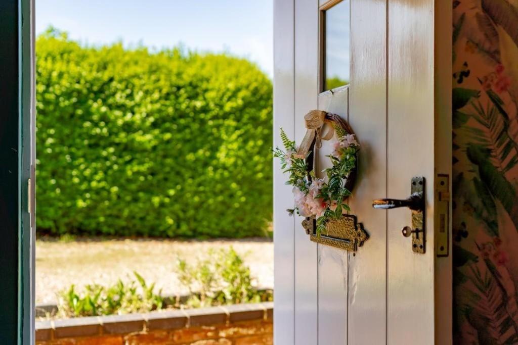 a bride looking out the door with her bouquet at Thyme Cottage in Beccles