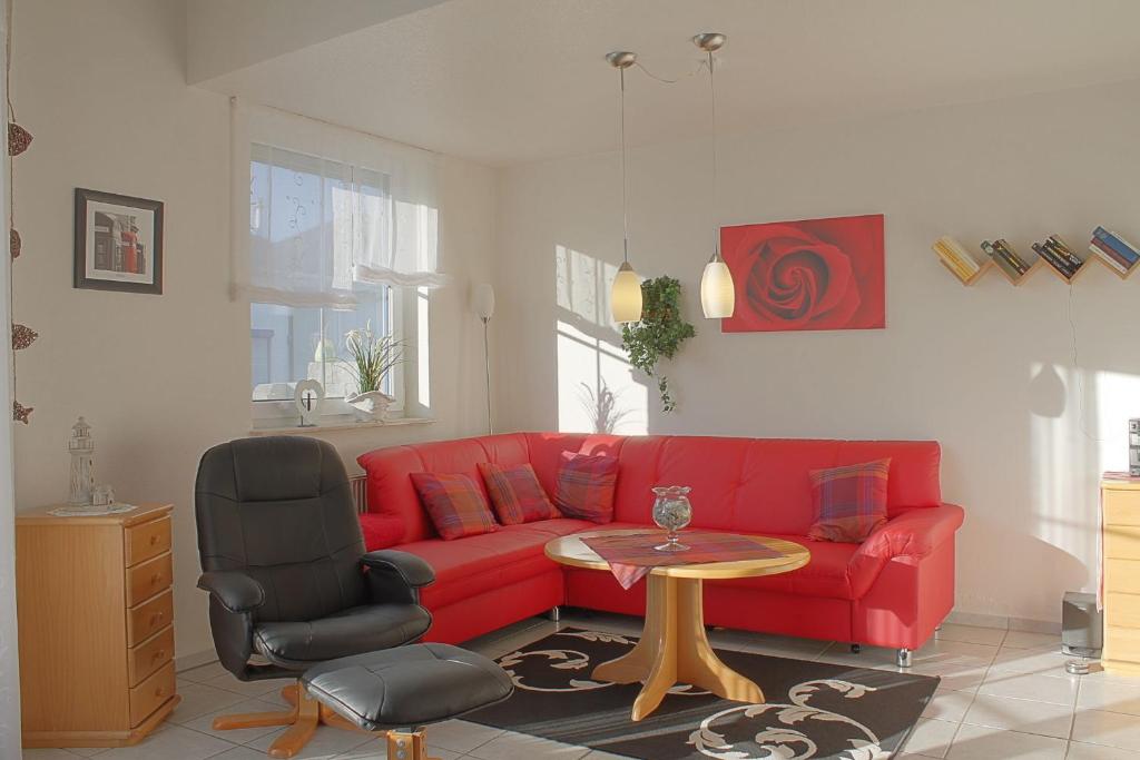a living room with a red couch and a table at LT 33a Bungalow Max in Dorum-Neufeld