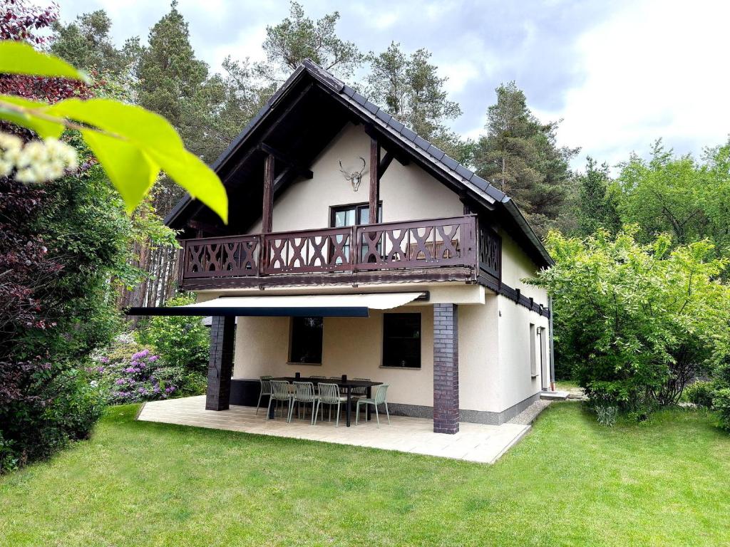 a house with a balcony and a table in the yard at Kiefernwäldchen in Byhlen
