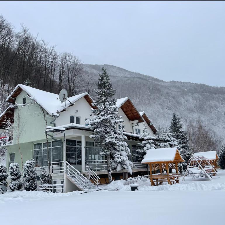a house covered in snow in front at Hotel Gryka in Peje