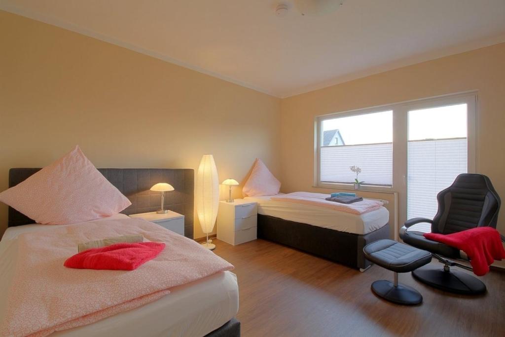 a bedroom with two beds and a chair and a window at Gästehaus Dorum 03 in Dorum