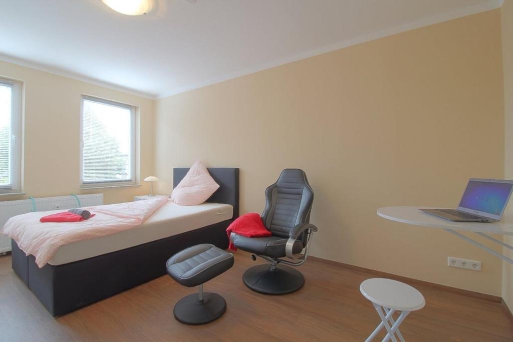 a bedroom with a bed and a chair and a laptop at Gästehaus Dorum 02 in Dorum