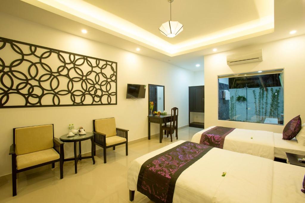 Habitación de hotel con 2 camas, mesa y sillas en Hoi An Hideaway Villa, en Hoi An