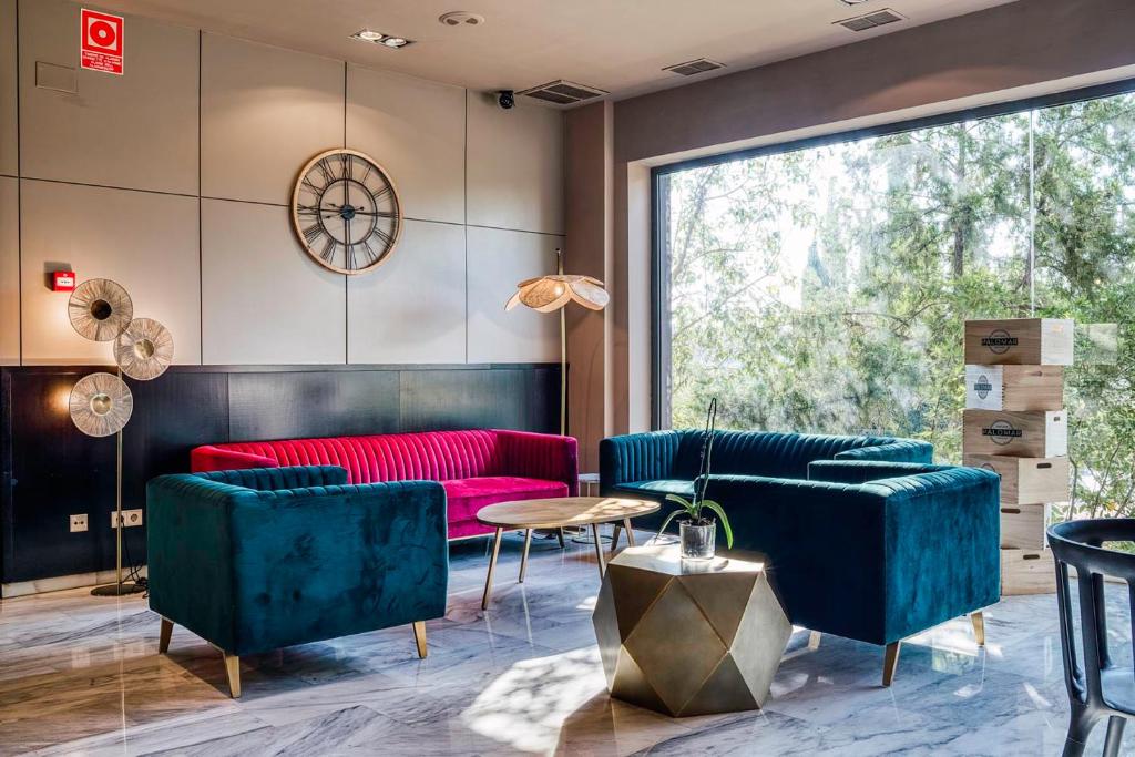 ein Wohnzimmer mit blauen und roten Möbeln und einem großen Fenster in der Unterkunft Hotel Ignacio - PalomarGroup in Chiva