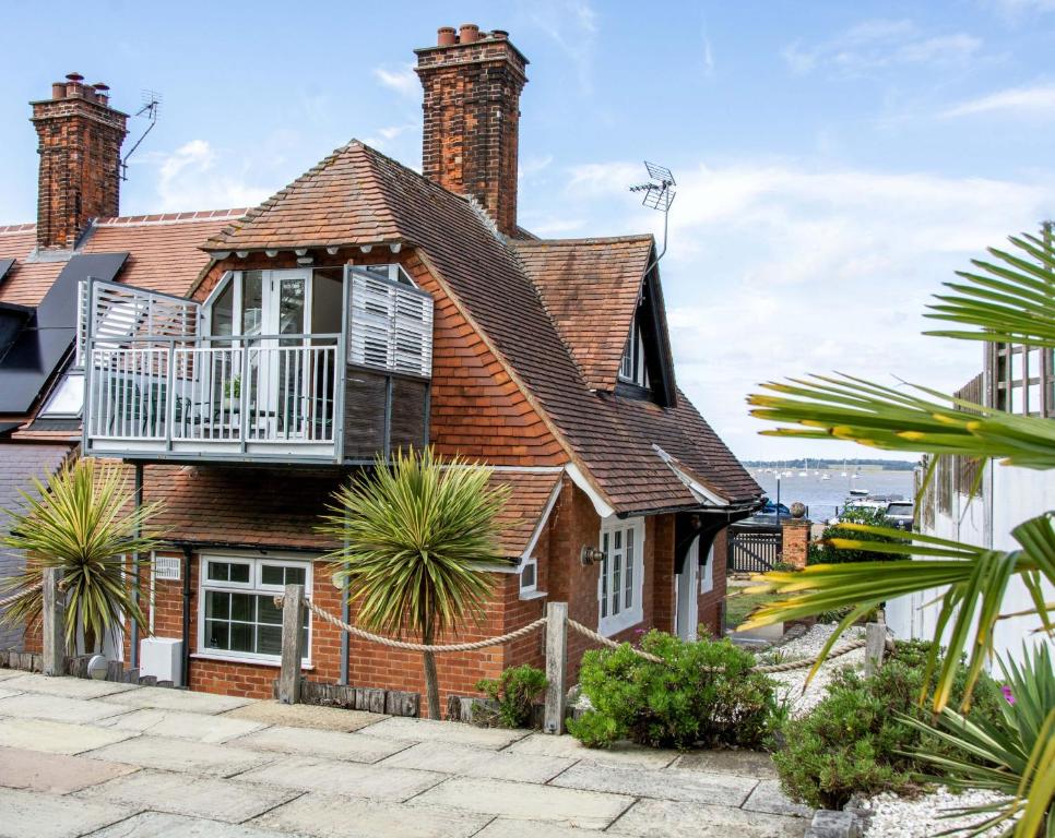 a brick house with a balcony on top of it at 1 Quay Cottage in Bawdsey