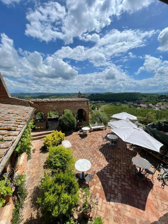 an outdoor patio with tables and umbrellas on a building at B&B Osteria Del Vicario in Certaldo