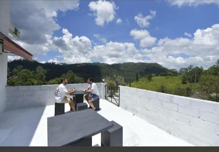 two men sitting at a table on a balcony at Wounder Mountain view ella in Medaperuwa