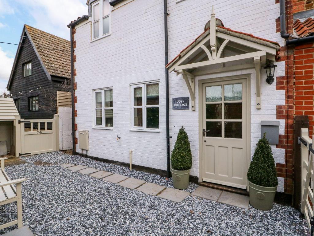 a white house with a door and two trees at Joy's Cottage in King's Lynn
