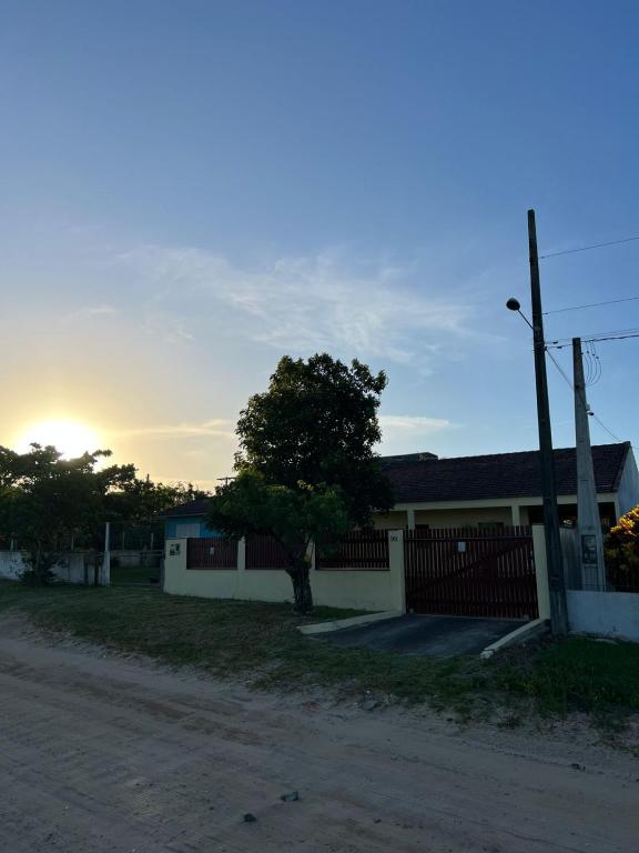 a house with a fence and a tree in front of it at Casa da lagoa in Imbituba
