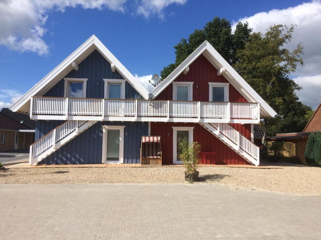 a red and blue house with a white balcony at Ferienwohnungen im Schwedenstil in Papenburg