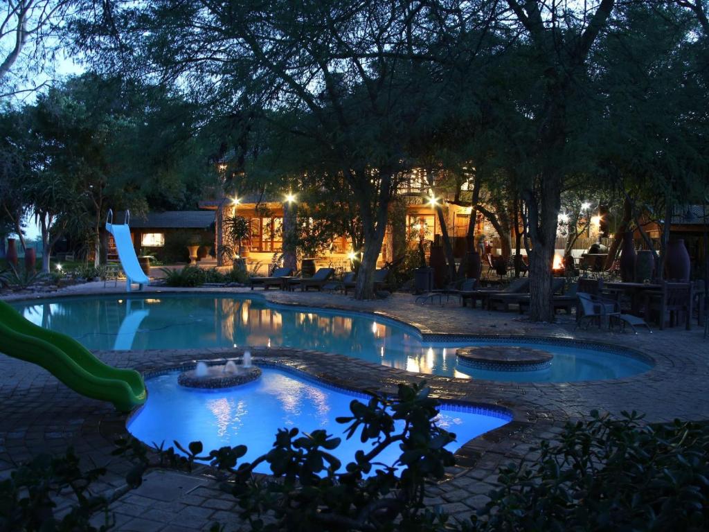 a pool with two fountains in a yard at night at Shelanti Game Reserve in Marken
