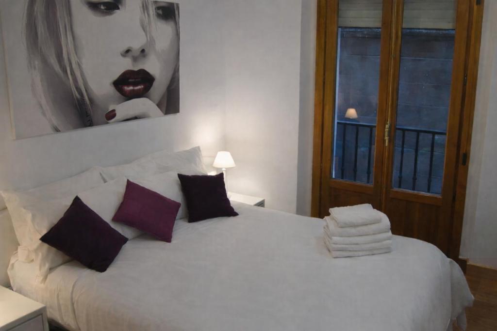 a bedroom with a white bed with a picture on the wall at Calle Ansoleaga a 100 mts del Ayuntamiento in Pamplona