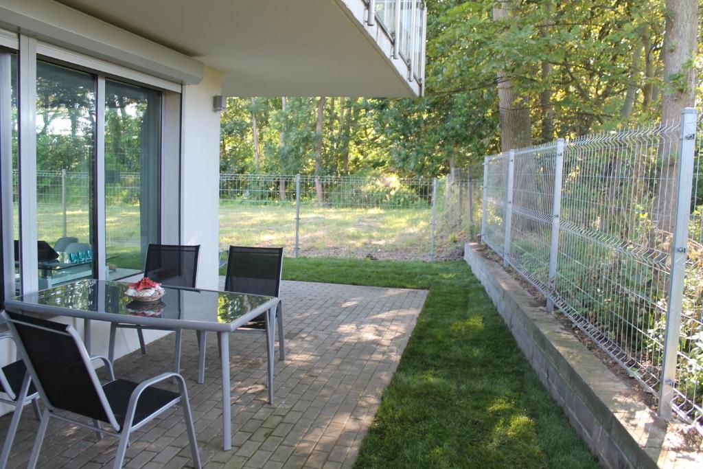un patio con mesa, sillas y una valla en Villa Klif, en Rewal
