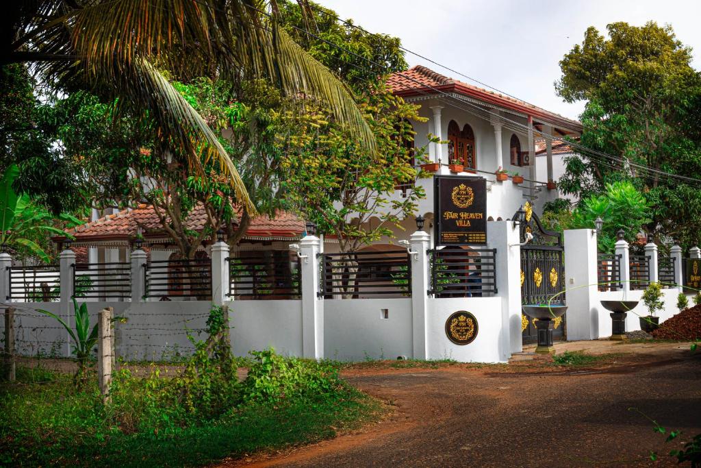 a white house with a fence in front of it at Fair Heaven Villa in Chilaw