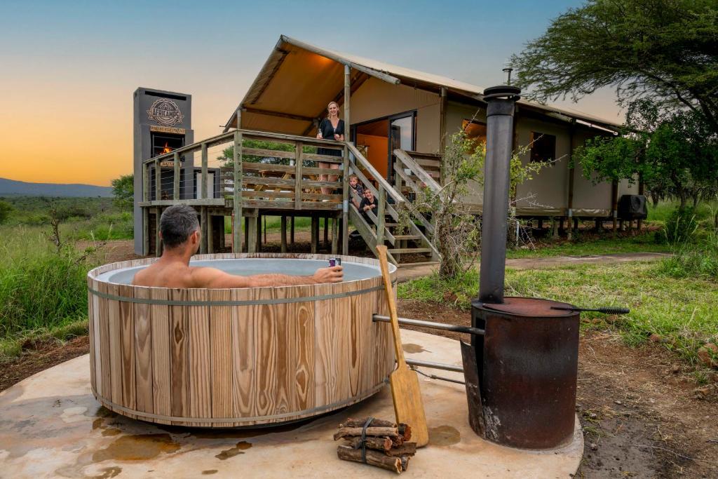 a man in a hot tub in front of a house at AfriCamps at White Elephant Safaris in Pongola Game Reserve