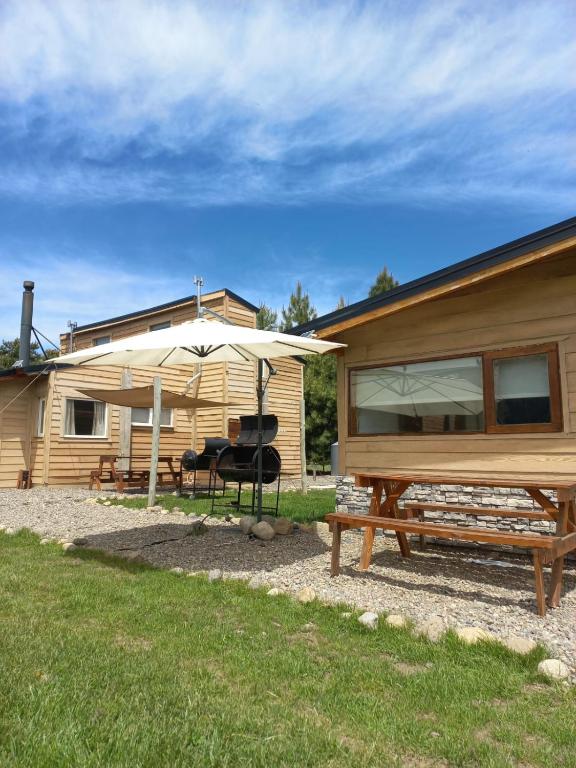 a house with a picnic table and an umbrella at Complejo Maylen Meliquina in Lago Meliquina