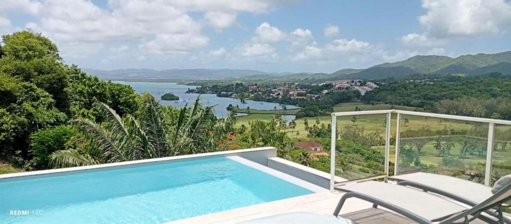a swimming pool with chairs and a view of the water at La Maison Bwa in Les Trois-Îlets