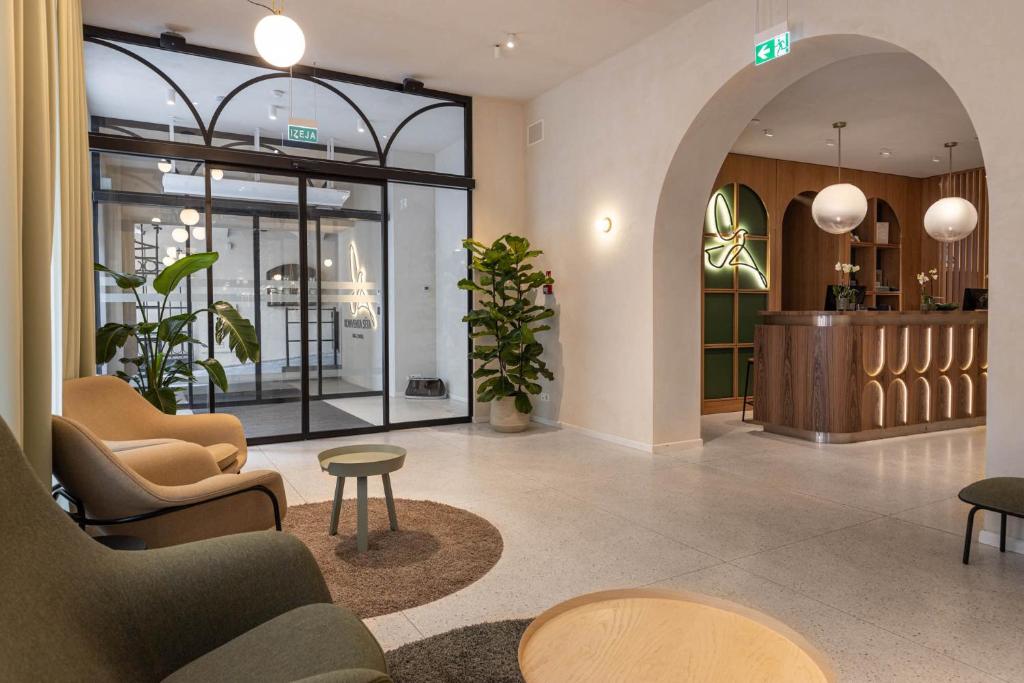 Lobby with arched glass entry, green-framed desk, lounge seating, indoor plants and terrazzo floor at Konventa Sēta Hotel - Keystone Collection in Riga