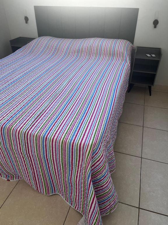 a bed with a striped comforter on top of it at Apto 2 quartos, Wi-Fi rápido, Self check in in Uberlândia