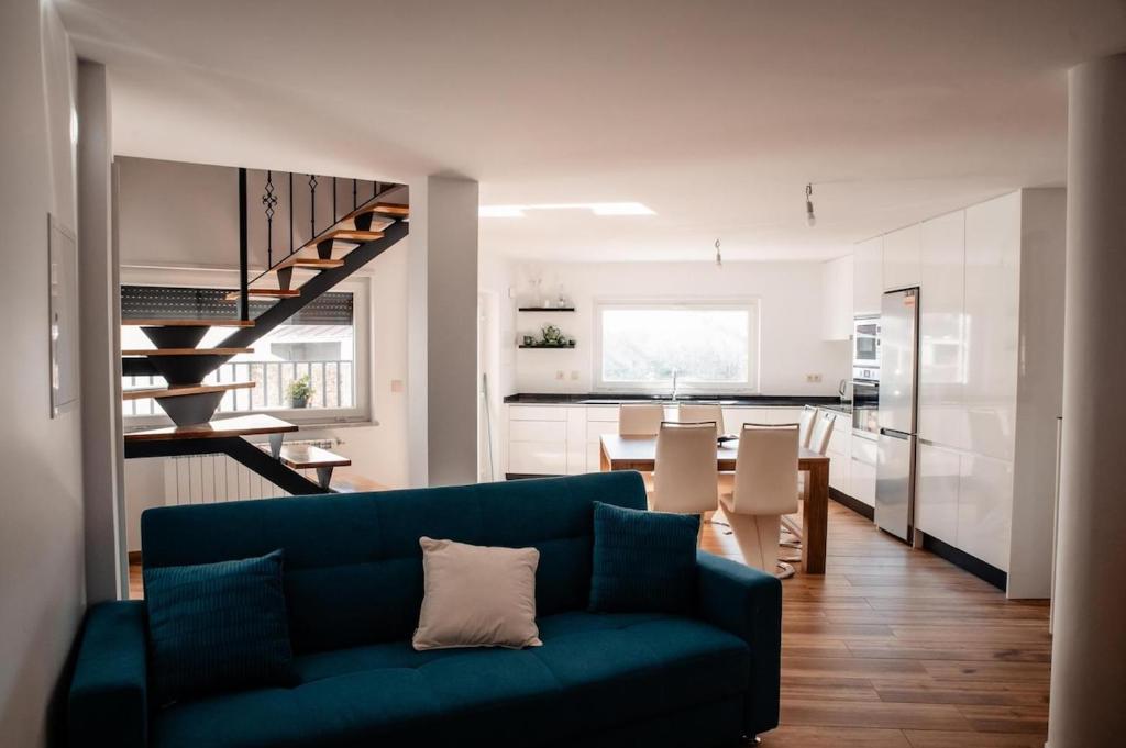 a living room with a blue couch and a kitchen at Casa da avo Rita in Pêro Viseu