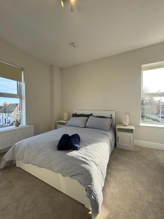 a bedroom with a large bed with two windows at Central Aldershot Flat, Near Station & Town Centre in Aldershot