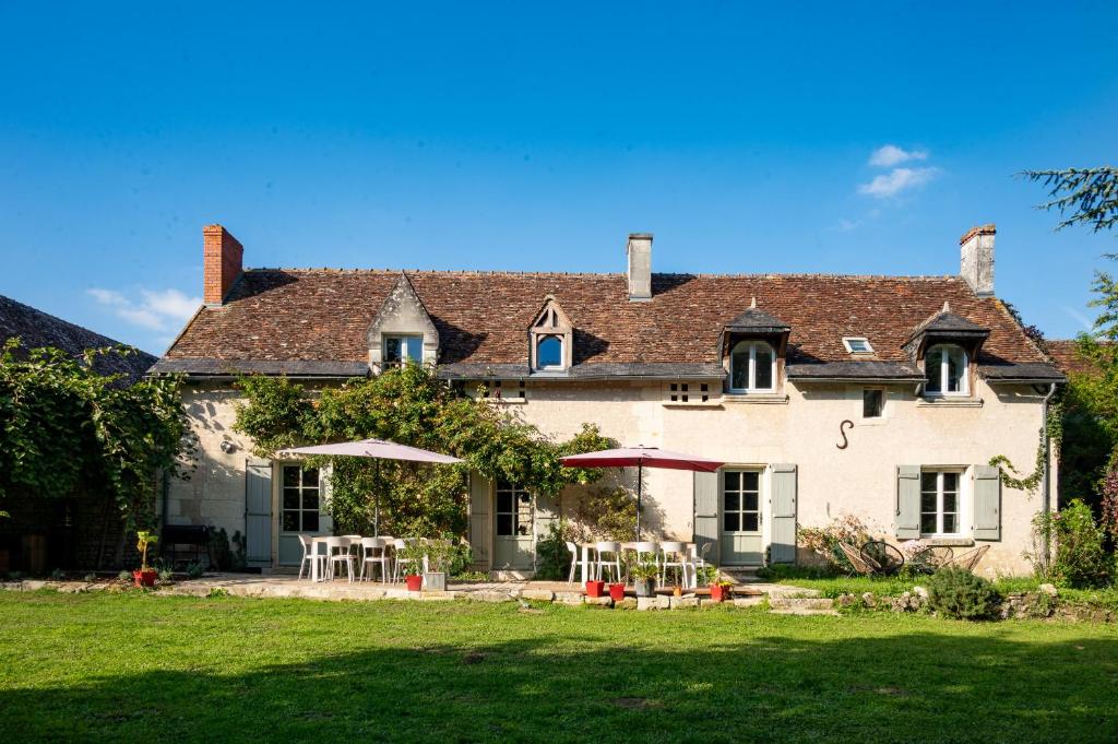 a large white house with tables and chairs in the yard at B&B BienViennue in Marcilly-sur-Vienne
