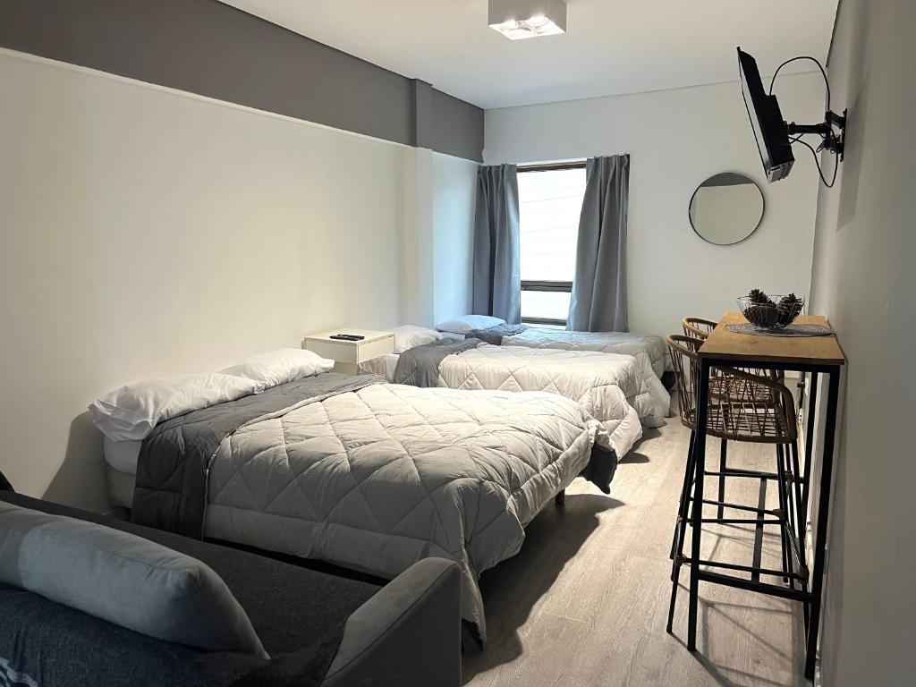 a bedroom with two beds and a table and a window at Apart hotel Ciudad de Bs As in Buenos Aires