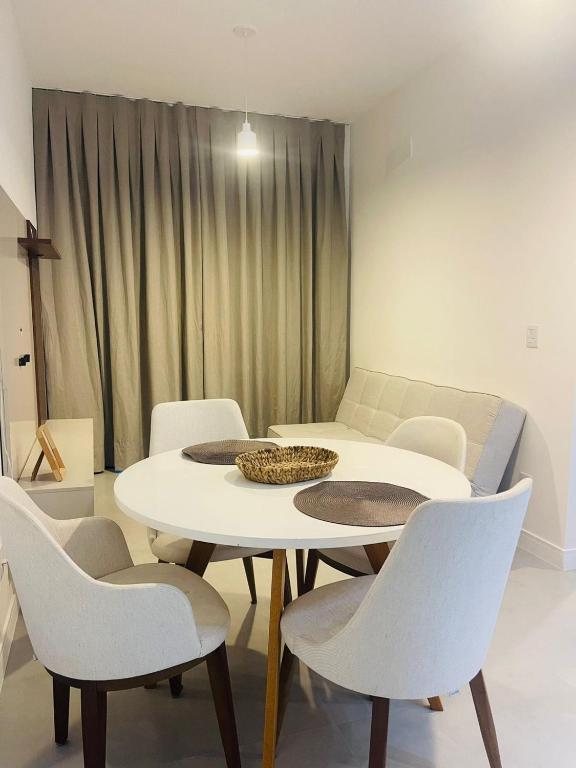 a dining room with a table and white chairs at Apartamento moderno no Centro de Cabo Frio in Cabo Frio