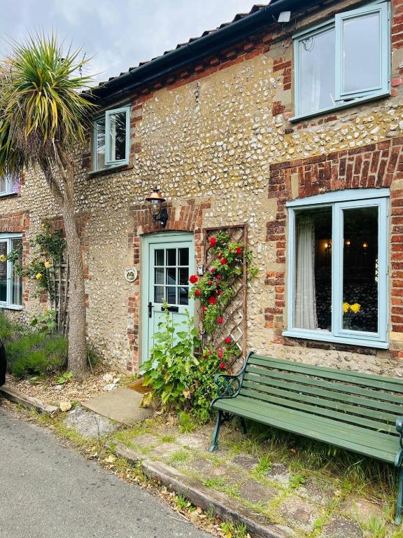 a brick house with a green bench in front of it at Staneve Cottage in Docking