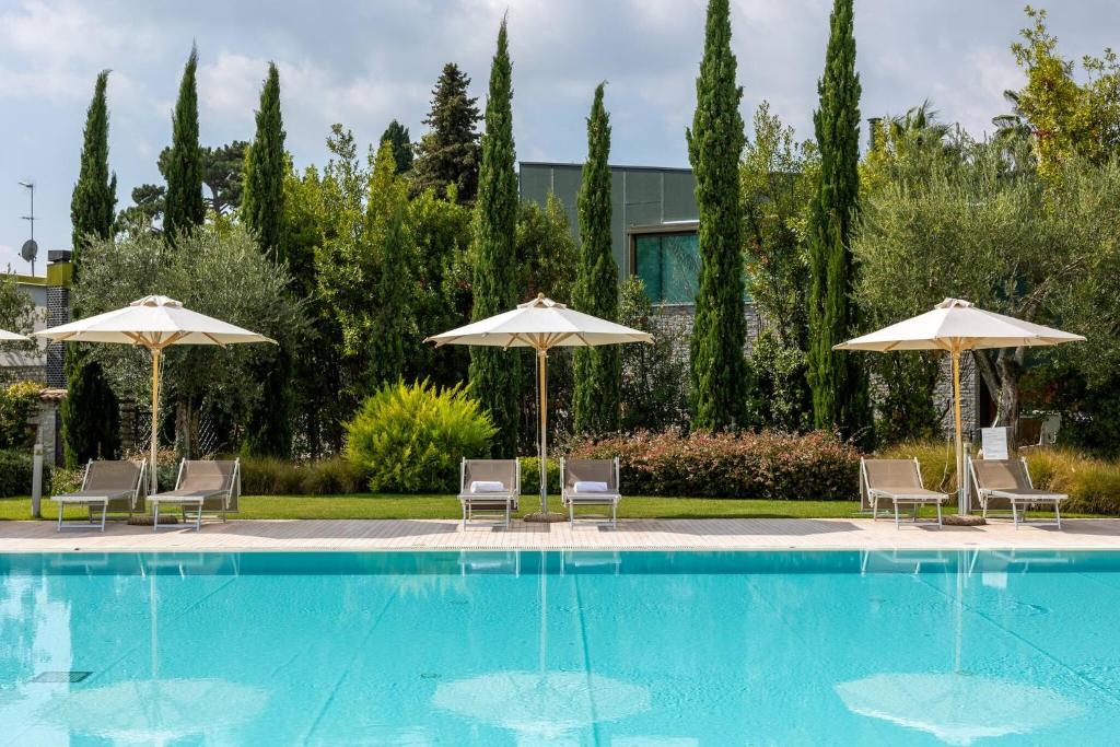 a swimming pool with chairs and umbrellas at Corte Fasanella 50 in Toscolano Maderno