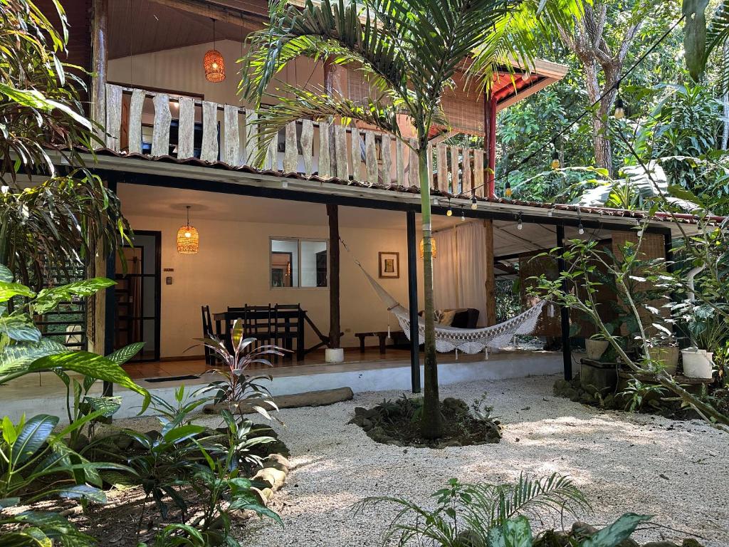 a house with a hammock in the middle of a garden at Colibri Apartments - Private kitchen & bathroom - 4 min walk to the Beach! in Santa Teresa Beach