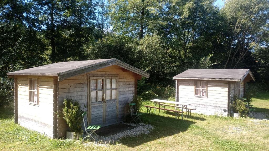 two small buildings in a field with a bench at Zehrermühle Campinghütte in Schönberg
