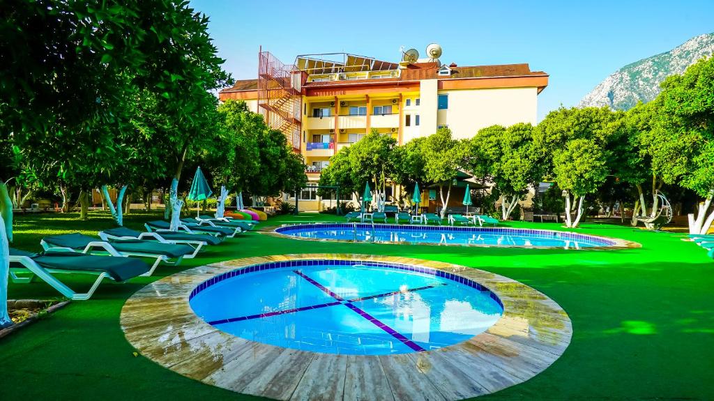 ein großes Schwimmbecken mit Liegestühlen und ein Gebäude in der Unterkunft CASTLE PARK HOTEL in Beldibi