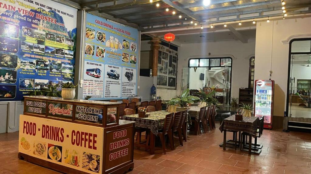 a restaurant with tables and chairs and posters on the wall at Mountain View Hostel in Bố Trạch