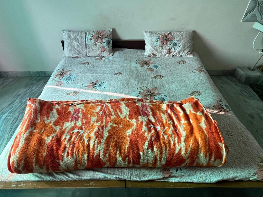 a bed with a comforter and pillows on it at Krishna guest house in Sāmbhar