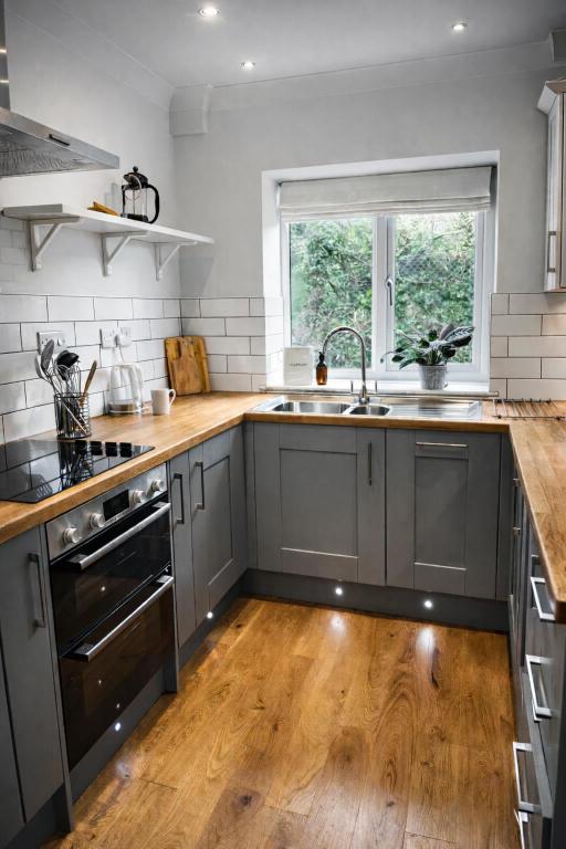 a kitchen with gray cabinets and a wooden floor at Fernhill Hideaway in Charmouth
