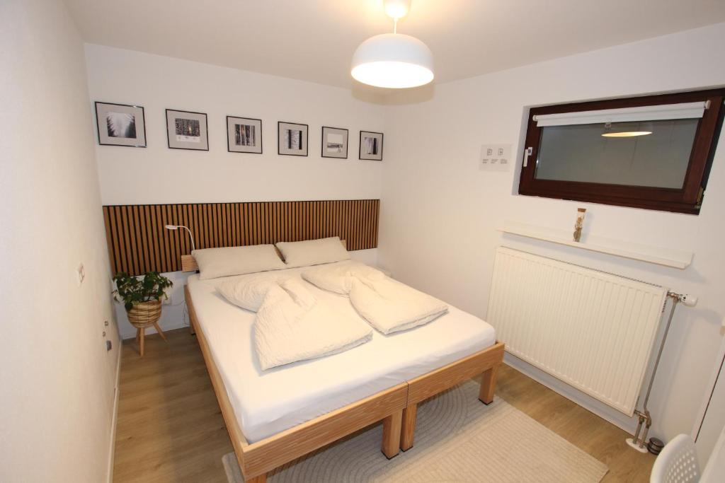 a bedroom with a bed with white sheets and a tv at Gemütliches Schwarzwald-Apartment im ruhigen Untergeschoss eines Hauses in Denzlingen