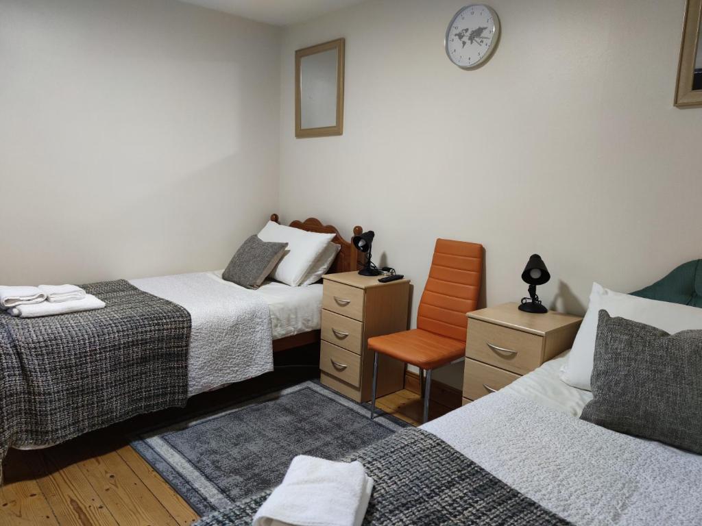 a bedroom with two beds and a chair and a clock at Bernie's Place - Homestay in Castlebar