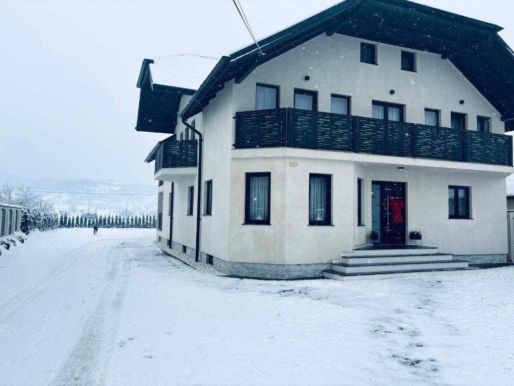 a white house with a red door in the snow at Casa Pop in Petrova