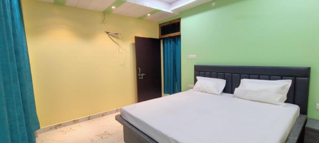 a bedroom with a white bed with a black headboard at Hanumant Dham in Dārāganj